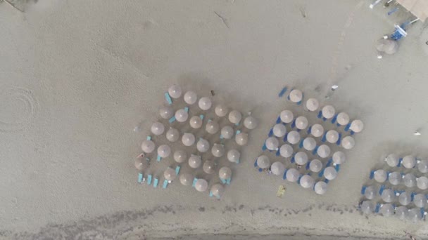 海岸には太陽の傘がたくさんある街のビーチの空中映像 — ストック動画