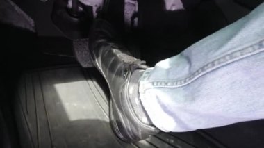 Siyah ayakkabılı adam araba kullanırken gaz pedalına basıyor..