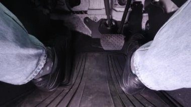 Siyah ayakkabılı adam araba kullanırken gaz pedalına basıyor..