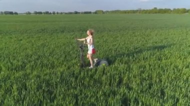 Hava görüntüsü. Doğa zindeliği. Genç bir kadın yeşil alanda stepper üzerinde çalışıyor. 4K.