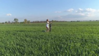 Hava görüntüsü. Doğa zindeliği. Genç bir kadın yeşil alanda stepper üzerinde çalışıyor. 4K.