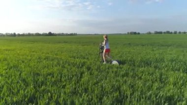 Hava görüntüsü. Doğa zindeliği. Genç bir kadın yeşil alanda stepper üzerinde çalışıyor. 4K.