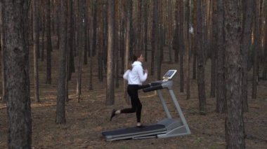 Genç bayan sporcu ormanda koşu bandında koşuyor. Dolly vurdu..