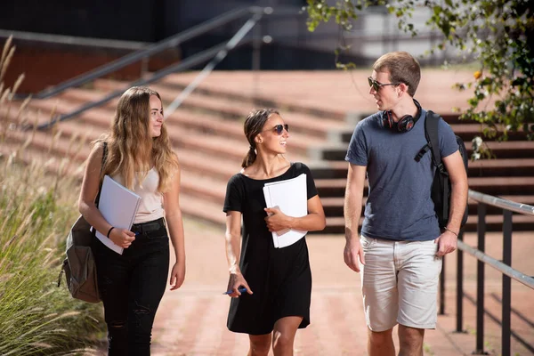 Three college students chatting while walking outdoors in the campus