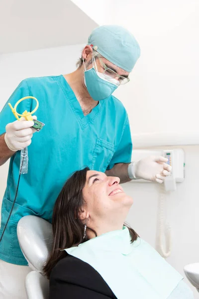 牙科医生和面带微笑的病人互相望着对方 同时推出X光工具 — 图库照片