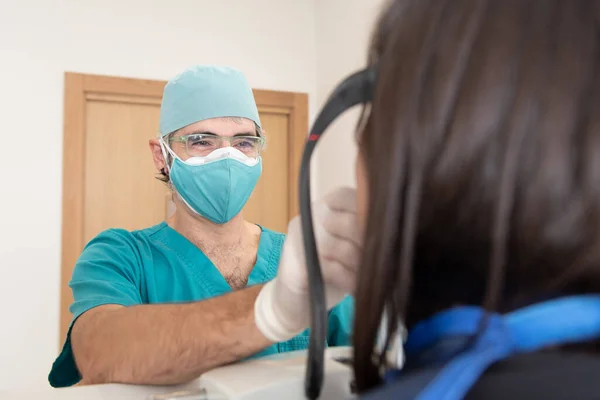 A smiling dentist preparing a patient to have a panoramic dental radiography using double mask during Coronavirus pandemic.