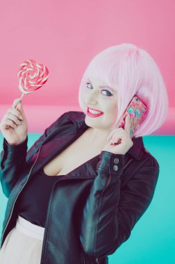 Lolipop ve elinde telefon ile poz pembe saçlı güzel genç şehvetli kadın