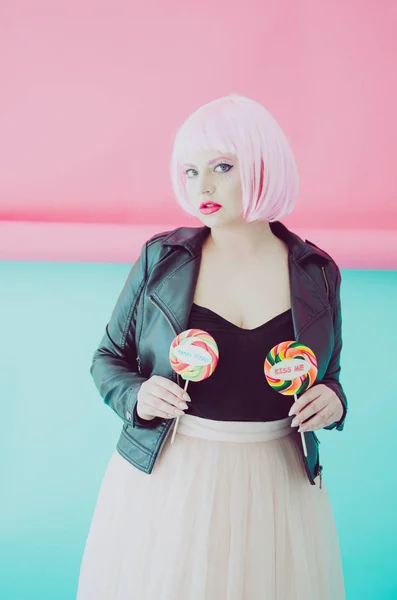 Beautiful young sensual woman with pink hair posing with lollypops