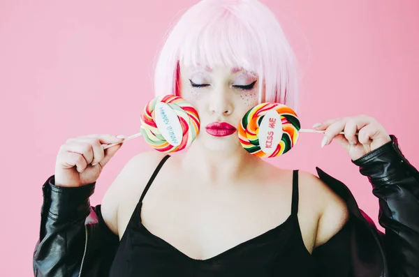 Beautiful young sensual woman with pink hair posing with lollypops