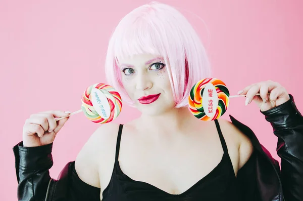 Beautiful young sensual woman with pink hair posing with lollypops