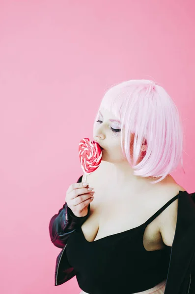 Beautiful young sensual woman with pink hair posing with lollypop