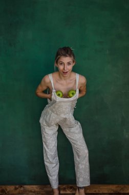 poz ve elma yeşil duvar arka planda tutan beyaz elbiseli Genç kadın