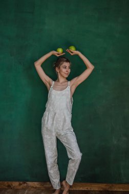 poz ve elma yeşil duvar arka planda tutan beyaz elbiseli Genç kadın