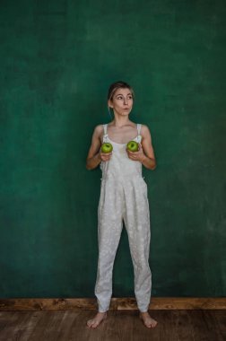 poz ve elma yeşil duvar arka planda tutan beyaz elbiseli Genç kadın