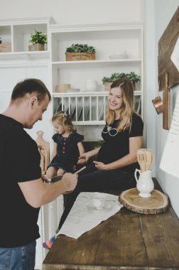 mutlu genç aile hamile kadın ve İskandinav mutfakta oturuyor ve having fun küçük kız