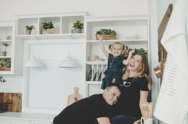 mutlu genç aile hamile kadın ve İskandinav mutfakta oturuyor ve having fun küçük kız