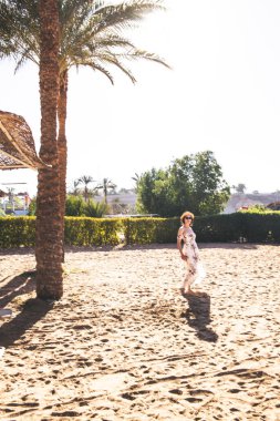 Gün batımında sahilde yürüyen bir kadın 