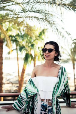 Tropikal plajda ileriye bakan bir kadın 