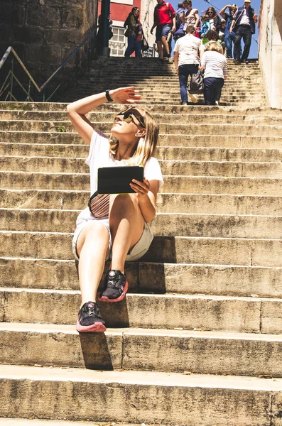 Joven turista sentado en las escaleras y mirando en la tableta —  Fotos de Stock