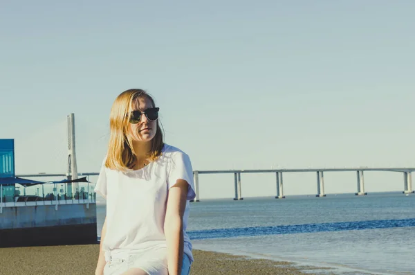 Junge Frau sitzt am Meer und freut sich — Stockfoto