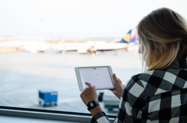 Havaalanında elinde tablet tutan ve mesaj yazan kadın. 