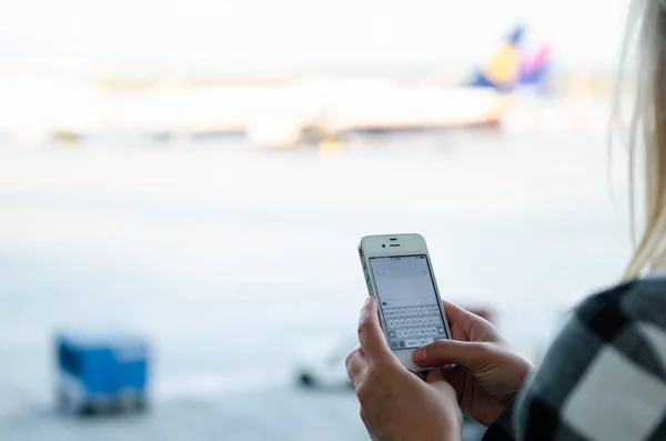 Woman holding phone and typing message at airport — Stock Photo, Image