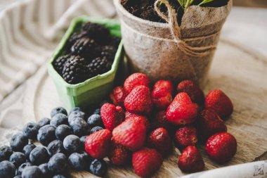 ahşap masada taze çilek yaban mersini ve böğürtlen