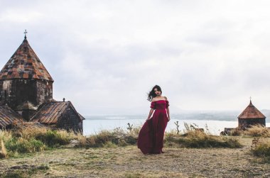 Manastırın yanında duran kırmızı elbiseli genç kadının portresi, Ar