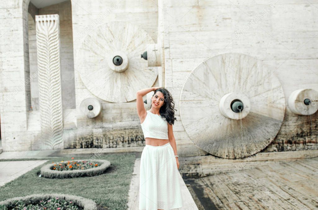 young woman in white dress outside posing and smiling 