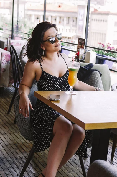Mulher franca em polka dot vestido beber coquetel no café — Fotografia de Stock