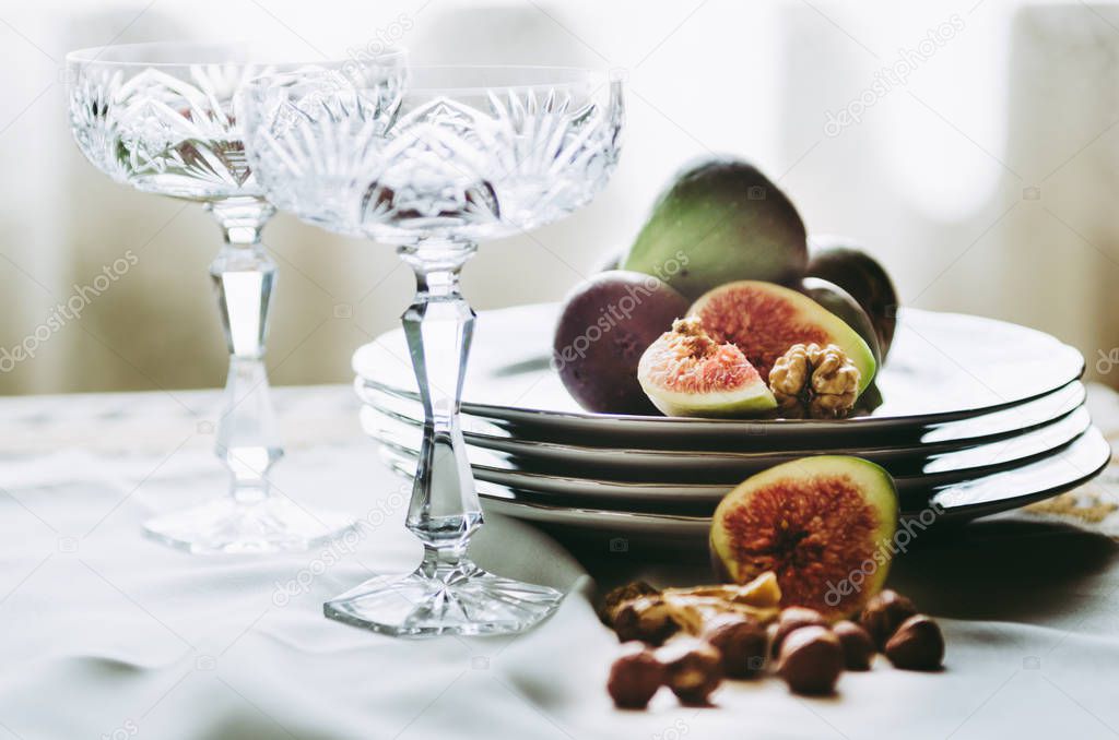 beautiful crystal champagne glasses with figs and nuts on table