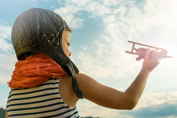 青い夏空を背景に木のおもちゃ飛行機で遊んで喜んでいる子供 — ストック写真