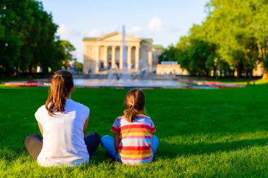 Grand Theatre - neoklasik opera house - Poznan, Polonya bulunuyor önünde parkta çim üzerinde batan güneşin ışınları içinde oturan çocuk