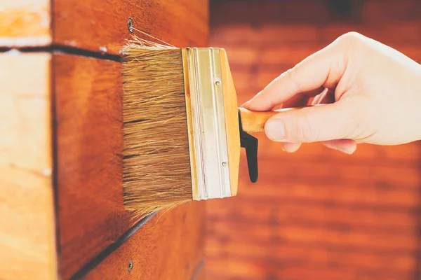 Male hand painting wooden wall with a brush