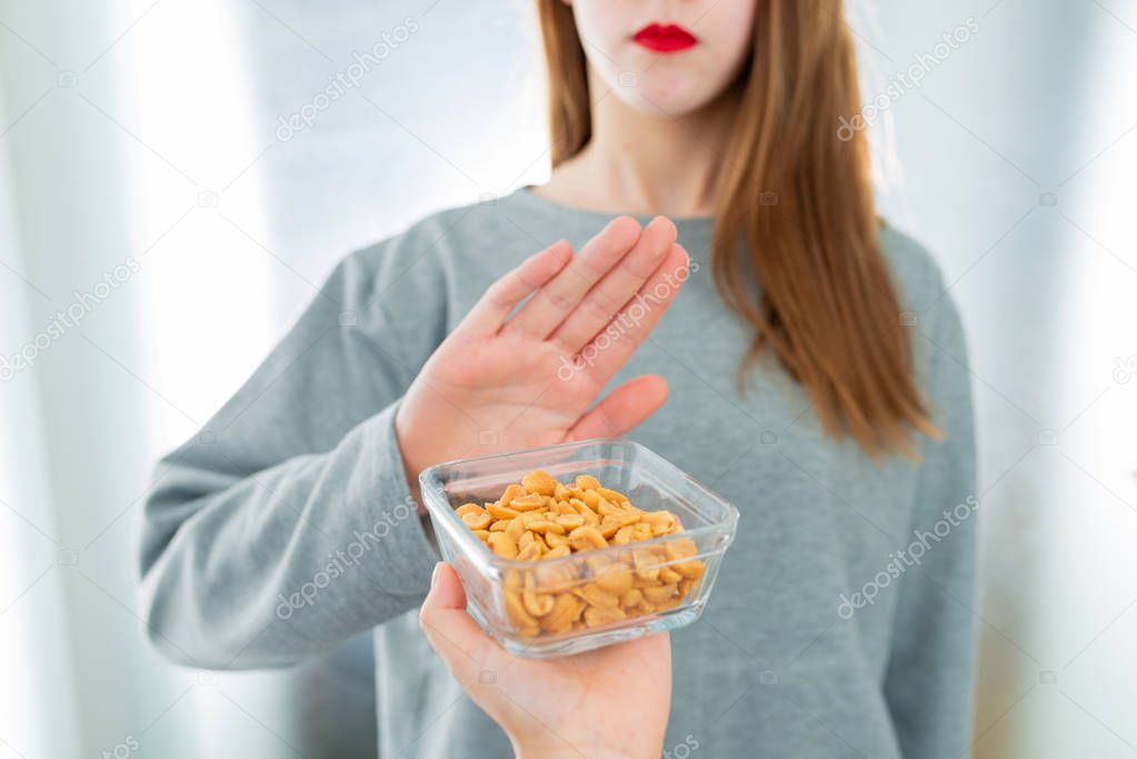 Peanut allergy concept - food intolerance. Young girl refuses to eat peanuts - shallow depth of field