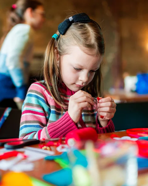 装飾芸術感じた縫製女の子子供のためのワーク ショップ 針を入れる小さな女の子のテーブルに横になっているカラフルな生地を合わせてください — ストック写真