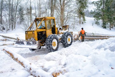 Ormancılık traktör ve dağ orman ahşap günlükleri verme kış sezonu boyunca sırasında anonim oduncu