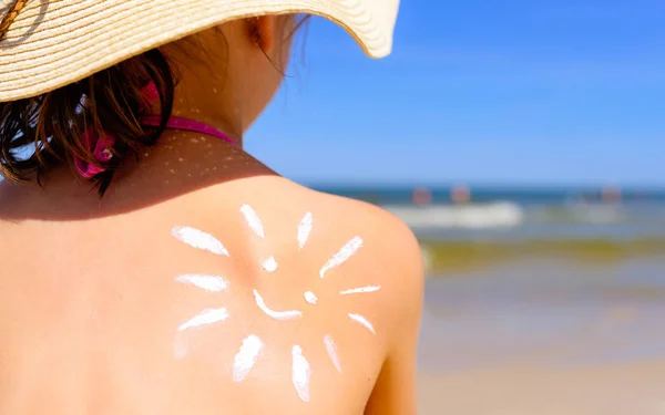 Mädchen mit Sonnencreme am Strand in Form der Sonne — Stockfoto