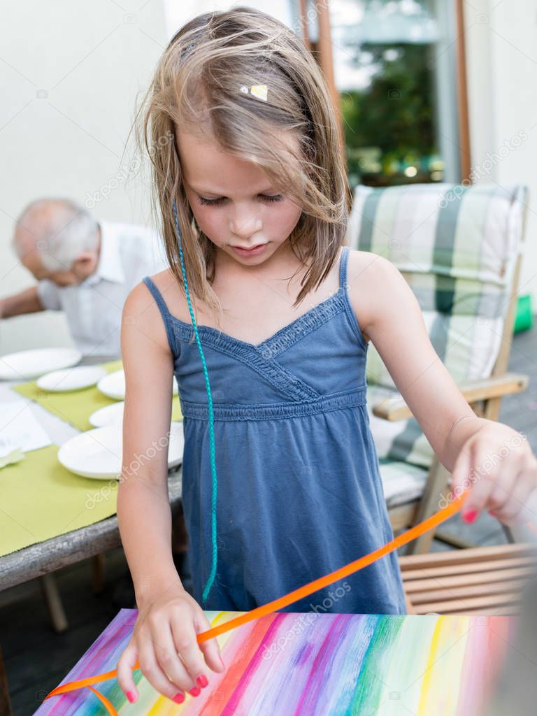 The little girl unwraps a birthday present during a garden party