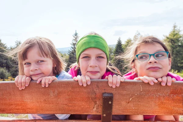 Tre sorelle in gita in montagna nascoste dietro una recinzione di legno — Foto Stock