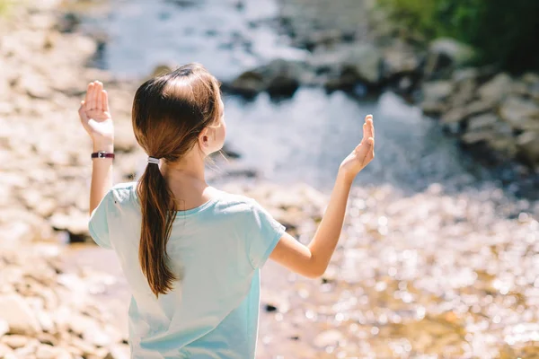 Genç kız bir dağın kıyısında dua kollarını kaldırır — Stok fotoğraf
