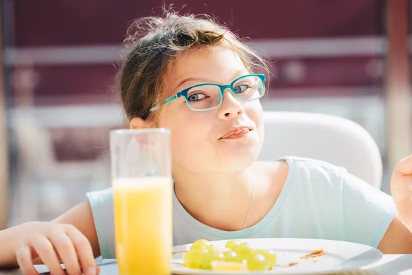 パンケーキ、新鮮な果物を食べてオレンジを飲む陽気な女の子 — ストック写真