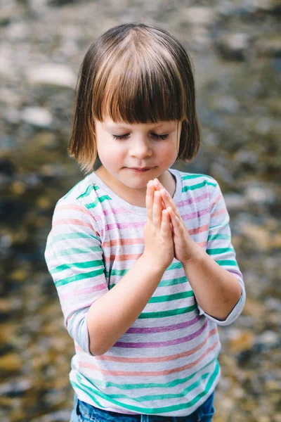 Маленькая девочка молится с закрытыми глазами — стоковое фото