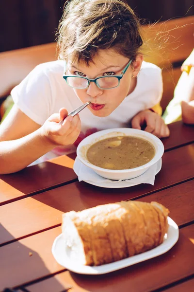 Petite fille dans des lunettes manger soupe chaude — Photo