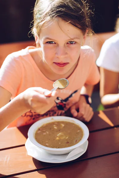 熱いスープを食べるピンクのTシャツの小さな女の子 — ストック写真