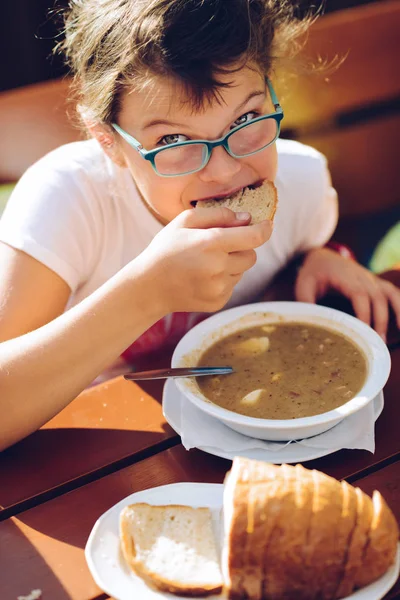 Petite fille dans des lunettes manger soupe chaude — Photo