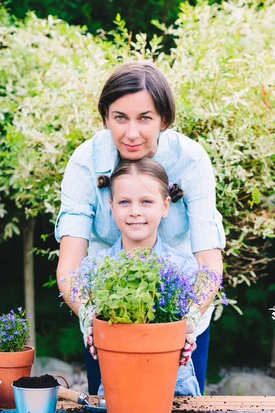 Mother and daughter planting flowers in pots in the garden — Stock Photo, Image