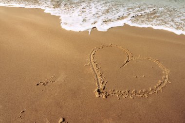 kumlu bir sahil plajında kalp şekli ahşap bir sopa ile çizilmiş