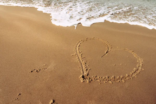 kumlu bir sahil plajında kalp şekli ahşap bir sopa ile çizilmiş