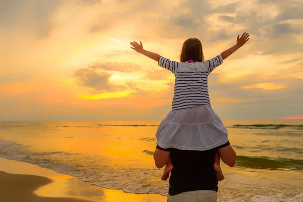Child on dad's shoulders on the background of the setting sun — Stock Photo, Image